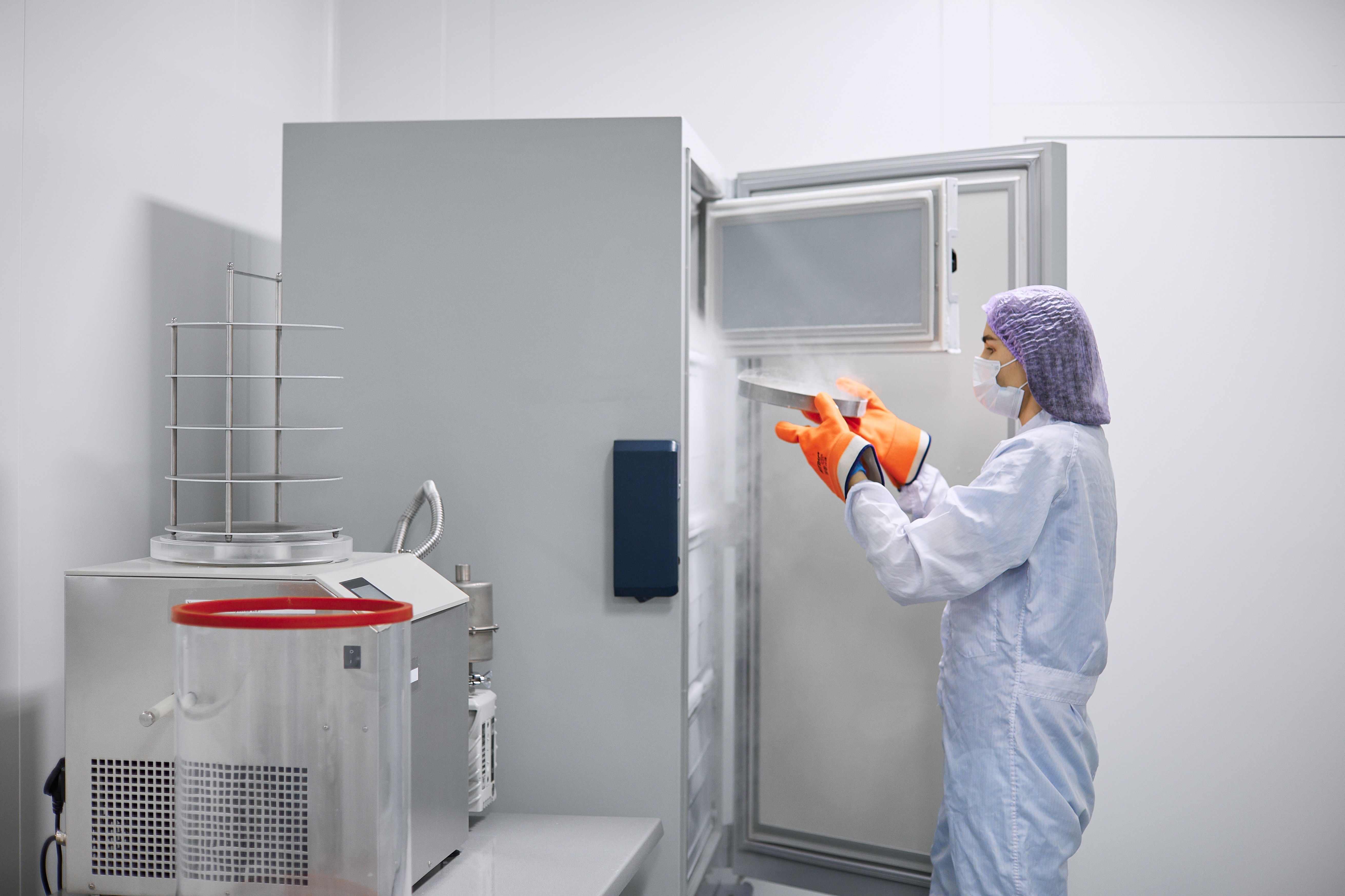 A scientist putting a sample in a large freezer
