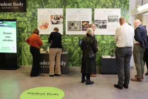 Members of the public engaging with displays and artefacts in the Student Body exhibition. Visitors viewing exhibits and reading interpretation panels in the Student Body exhibition space.]