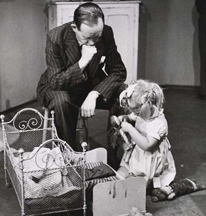 Photograph of John Bowlby observing a young child playing with a doll.