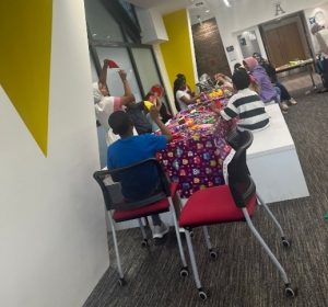 Children are sitting around a table doing origami.