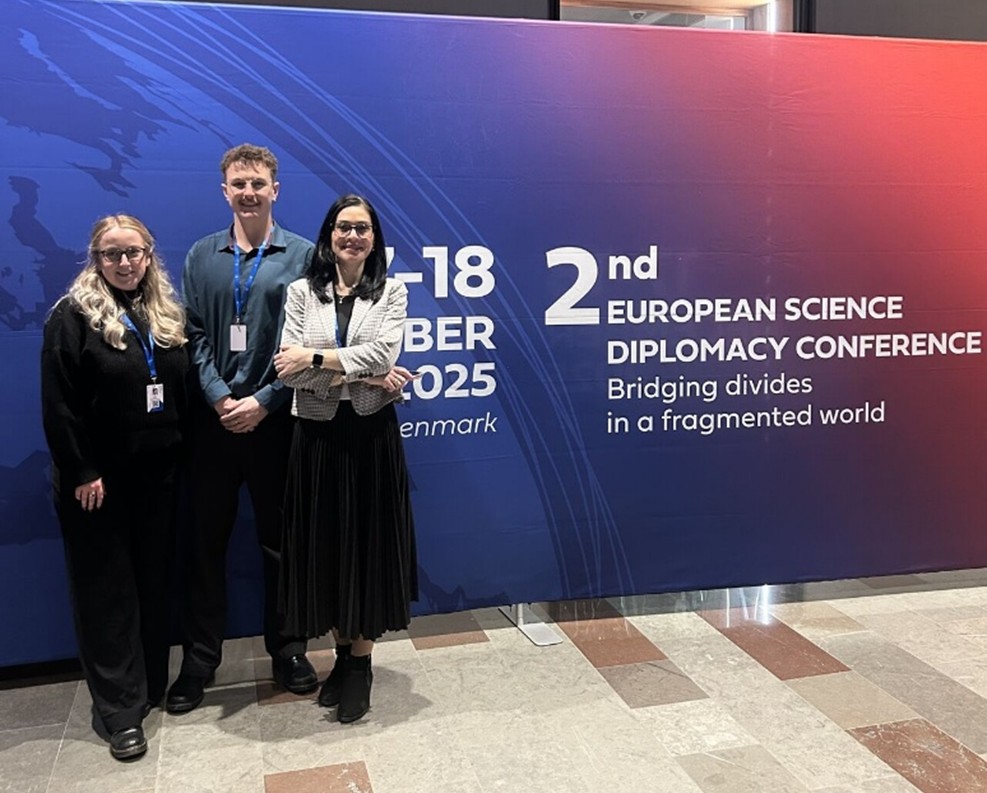 A group of people standing in front of a conference sign