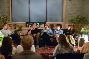 Panel discussion with five male and female speakers seated on a couch in front of an audience under a “Talking Threads” sign.