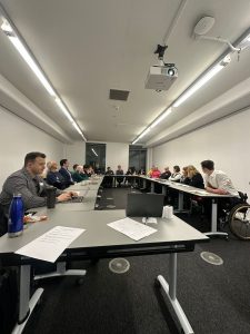 Group of people sat across tables talking